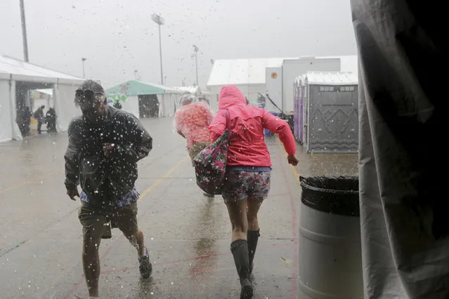 Festival-goers run from the downpour at the WWOZ Jazz tent at the New Orleans Jazz & Heritage Festival New Orleans, Thursday, April 25, 2019. The opening was delayed by heavy rain. (Photo by Doug Parker/AP Photo}
