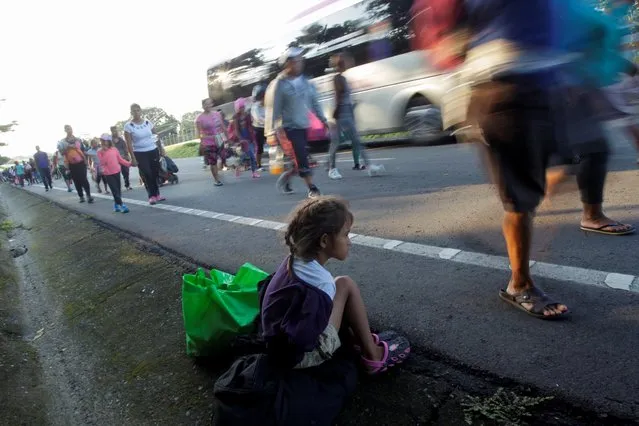 A migrant girl rests from walking as she takes part in a caravan with her father heading to Mexico City, in Mapastepec, Mexico on November 1, 2021. (Photo by Daniel Becerril/Reuters)