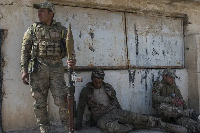 Injured Iraqi Emergency Response Division (ERD) soldiers hit by mortar shrapnel wait for medics to arrive at the Islamic State occupied Mosul Airport in west Mosul, part of the offensive to retake the city some two years after it fell to the hardline jihadist group, February 23, 2017. Iraqi forces encountered stiff resistance with improvised explosives, heavy mortar fire and snipers hampering their advance before they successfully took the airport. (Photo by Martyn Aim/Getty Images)