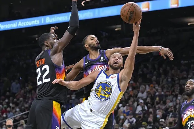 Golden State Warriors guard Stephen Curry (30) shoots between Phoenix Suns center Deandre Ayton (22) and guard Cameron Payne during the first half of an NBA basketball game Saturday, December 25, 2021, in Phoenix. (Photo by Rick Scuteri/AP Photo)