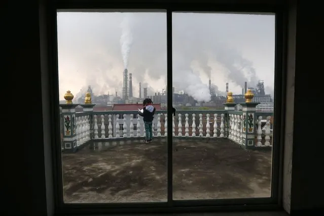 A girl reads a book on her balcony as smoke rises from chimneys of a steel plant, on a hazy day in Quzhou, Zhejiang province, on April 3, 2014. (Photo by Reuters/Stringer)