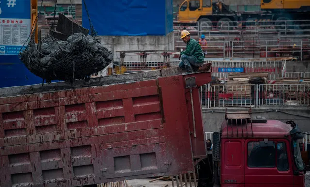 A man works on a truck at a construction site for a high- rise building in Shanghai on March 5, 2017. (Photo by Johannes Eisele/AFP Photo)