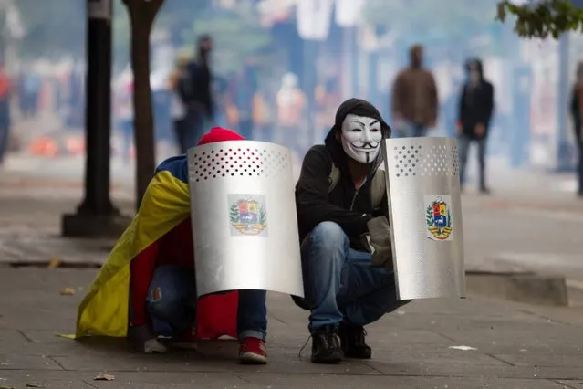 Opposition demonstrators try to take cover behind shields during clashes with police in Chacao, Caracas, April 16, 2014. Protests against Venezuelan President Nicolas Maduro's government have left 41 people dead and more than 650 injured, according to authorities. Maduro, the hand-picked successor to the late Venezuelan president Hugo Chavez, has accused demonstrators of trying to topple his government. (Photo by Miguel Gutierrez/EPA)