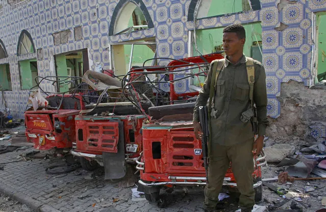 Security forces stand near the wreckage of three-wheeled vehicles destroyed in a bomb attack in the capital Mogadishu, Somalia Saturday, June 15, 2019. (Photo by Farah Abdi Warsameh/AP Photo)