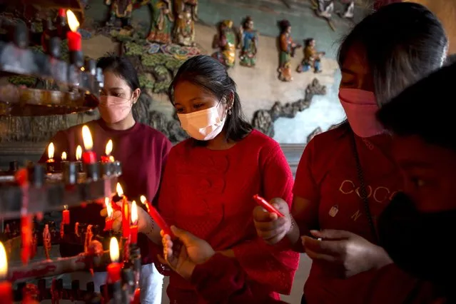 Ethnic Chinese worshipers wearing face masks to help curb the spread of the coronavirus pray to celebrate the Lunar New Year at a temple in Bali, Indonesia, Tuesday, February 1, 2022. People across Asia prepared Monday for muted Lunar New Year celebrations amid concerns over the coronavirus and virulent omicron variant, even as increasing vaccination rates raised hopes that the Year of the Tiger might bring life back closer to normal. (Photo by Firdia Lisnawati/AP Photo)