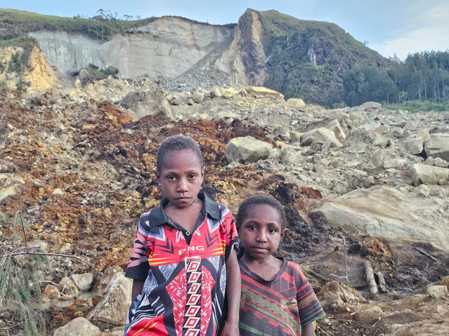 Children are seen at the destroyed area after a massive landslide struck a village in Enga Province, Papua New Guinea on May 27, 2024. The site's remoteness, ongoing terrain movement and damage to access roads caused relief efforts to slow as government authorities remain focused on clearing debris and improving access to the site. While the exact number of victims is still not known, affected communities estimate that at least 670 people are missing following the landslide, this number is subject to change as rescue efforts are ongoing and expected to continue for days. (Photo by Emmanuel Eralia/Anadolu via Getty Images)
