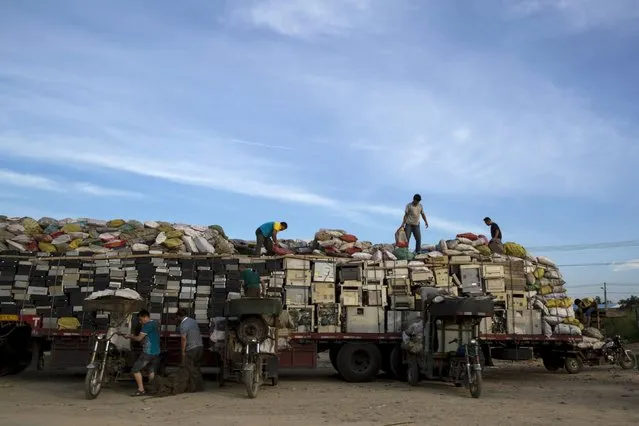 Workers illegally distribute old computers and printers to others for future recycling outside the government designated recycling centre, at the township of Guiyu in China's southern Guangdong province June 8, 2015. (Photo by Tyrone Siu/Reuters)