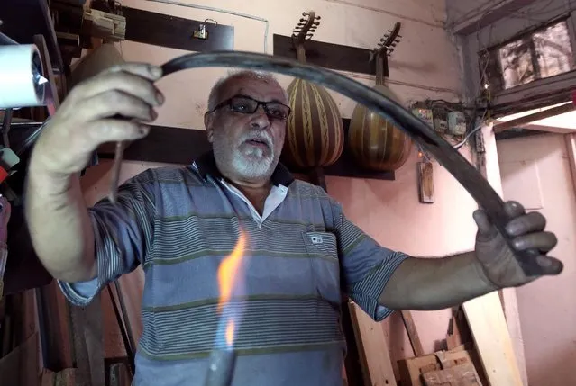 In this photo Saturday, June 20, 2015, Oud maker Mahmoud Abdulnabi uses fire to bend wood to shape at his workshop in Baghdad, Iraq. (Photo by Hadi Mizban/AP Photo)