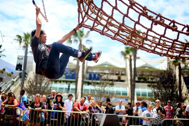 Carlin Stella grabs onto netting while doing an obstacle course at the “Assassins Creed Syndicate” booth outside of the 2015 Comic-Con International in San Diego, California July 10, 2015. (Photo by Sandy Huffaker/Reuters)