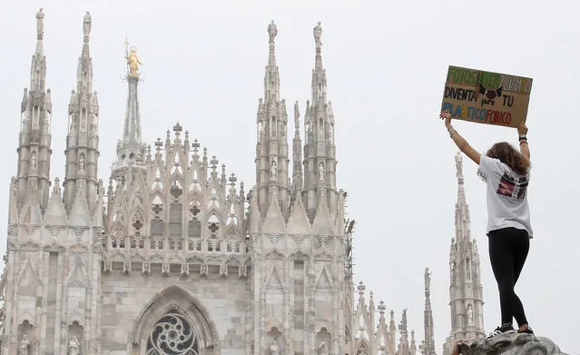 A girl holds up a card with writing reading in Italian "Lets photosynthesize, also you become plastic phobic"during a worldwide protest demanding action on climate change in front of Milan's gothic cathedral, Italy, Friday, September 27, 2019. The protests are inspired by Swedish teenager Greta Thunberg, who spoke to world leaders at a United Nations summit this week. (Photo by Antonio Calanni/AP Photo)