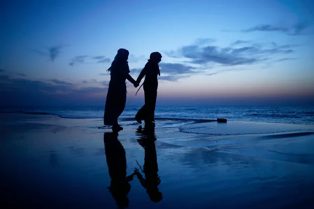 Palestinian girls walk holding hands at sunset on the beach in Gaza City as people around the world mark International Women' s Day on March 8, 2017. (Photo by Mohammed Abed/AFP Photo)