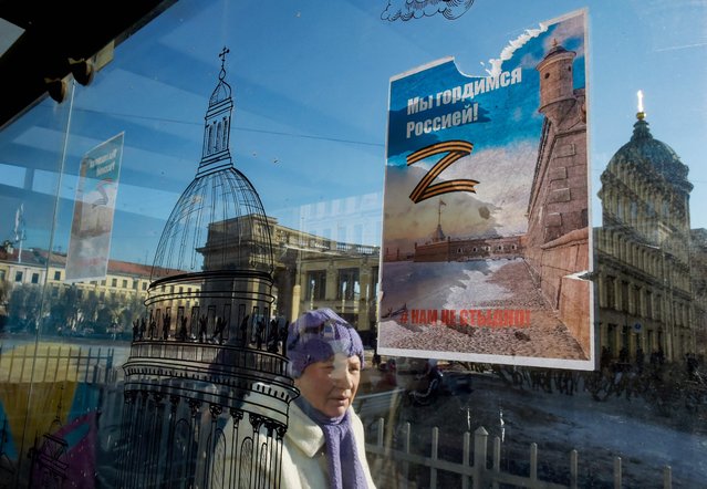 A woman walks past posters bearing the letter “Z” in the colours of the ribbon of Saint George, which has become a symbol of support for Russian military action in Ukraine, and reading “We are proud of Russia! We are not ashamed!” at a bus stop on Nevsky Prospekt in central Saint Petersburg on March 15, 2022. (Photo by AFP Photo/Stringer)