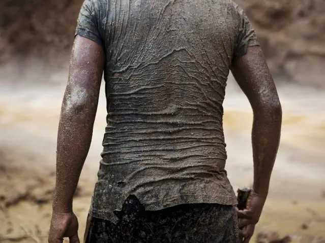 A miner continues his search for gold in mud-drenched clothes inside a crater at an illegal gold mine process in La Pampa in Peru's Madre de Dios region. The government claims that the informal miners have destroyed the surrounding forests and polluted the environment by using mercury in the gold extraction process. (Photo by Rodrigo Abd/AP Photo)