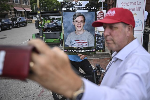 A man takes a self-made photo of a poster of Thomas Matthew Crooks, the man that attempted to assassinate former President Donald Trump stands on Water street during the third day of the 2024 Republican National Convention near the Fiserv Forum, Wednesday, July 17, 2024, in Milwaukee. (Photo by Joe Lamberti/AP Photo)