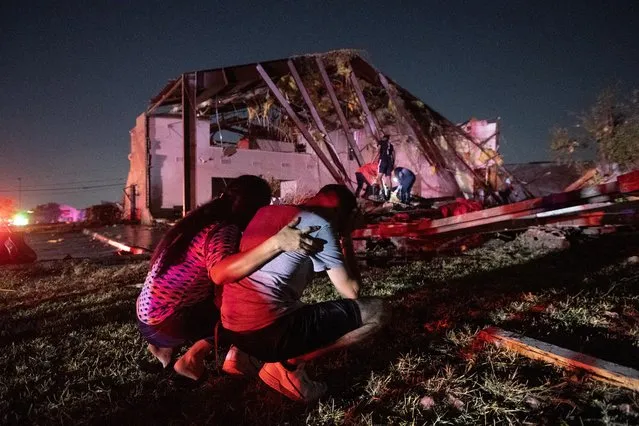 In this Sunday, October 20, 2019 photo, Henry Ramirez, a member of Primera Iglesia Dallas, is consoled by his mother Maribel Morales as they survey severe damage to the church, where Ramirez plays drums and Morales attends, after a tornado tore through North Dallas. (Photo by Jeffrey McWhorter/AP Photo)