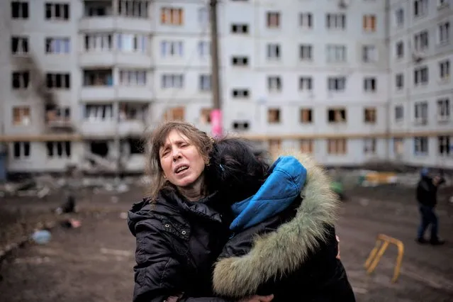 A woman reacts as she hugs another woman outside a heavily damaged apartment block, following an artillery attack, amid Russia's attack on Ukraine, in Kharkiv, Ukraine, April 13, 2022. (Photo by Alkis Konstantinidis/Reuters)