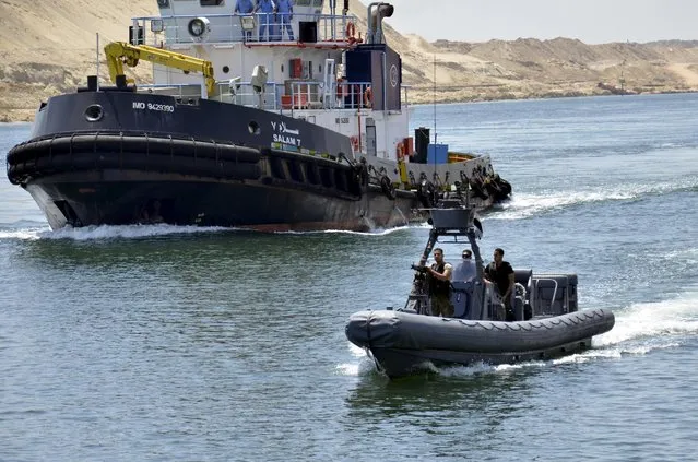 Security personnel are seen near a cargo ship crossing through the New Suez Canal, Ismailia, Egypt, July 25, 2015. The first cargo ships passed through Egypt's New Suez Canal on Saturday in a test-run before it opens next month, state media reported, 11 months after the army began constructing the $8 billion canal alongside the existing 145-year-old SuezCanal. Mohab Mameesh, chairman of the Suez Canal Authority overseer of the project, told state television that this test-run had been a success and that more would follow. (Photo by Reuters/Stringer)