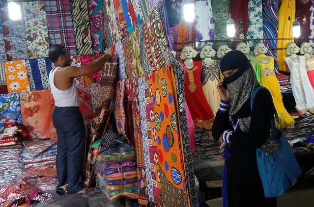 A veiled Muslim woman speaks on her mobile phone as a shopkeeper arranges clothes inside his roadside shop in Kolkata, India May 30, 2016. (Photo by Rupak De Chowdhuri/Reuters)