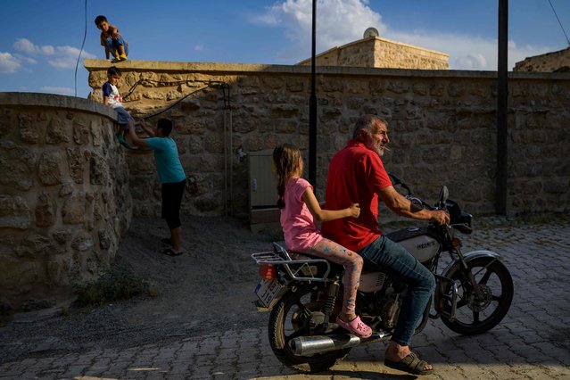 A motorcyclist rides near the Matiate archaeological site underneath the town in Midyat in Mardin province, southeastern Turkey, on July 1, 2024. Archaeologists stumbled upon the city-under-a-city “almost by chance” after an excavation of house cellars in the city of Midyat led to the discovery of a vast cave system in 2020. (Photo by Yasin Akgul/AFP Photo)