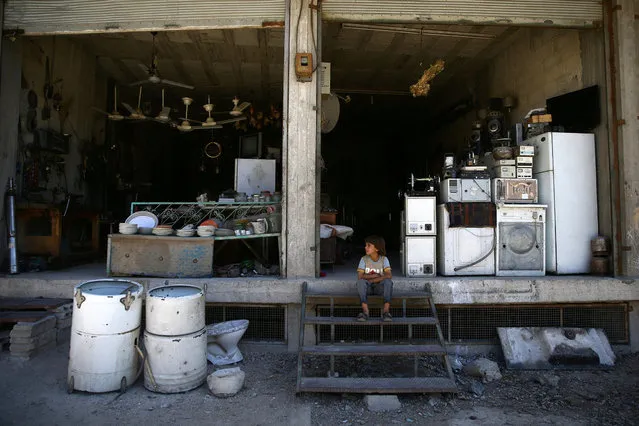 A boy sits outside a shop in the rebel held besieged eastern Damascus suburb of Ghouta, Syria May 24, 2017. (Photo by Bassam Khabieh/Reuters)