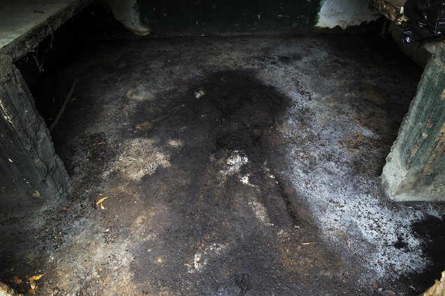 The figure of a human body stains the floor of a morgue inside the municipal cemetery in Cabimas, Venezuela, November 24, 2019. Some overcome the financial burden of a relative's death by renting caskets, turning to amateur morticians, and converting wooden furniture into coffins. (Photo by Rodrigo Abd/AP Photo)