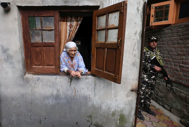 An Indian paramilitary soldier (R) stands guard as a Kashmiri Muslim elderly woman watches from her window during a door-to-door campaign of Bharatiya Janata Party (BJP) candidate Ashok Bhat (not pictured) for the upcoming assembly elections, in the Habba Kadal area of Srinagar, the summer capital of Indian Kashmir, 29 August 2024. India’s Election Commission on 16 August announced that Jammu and Kashmir Legislative Assembly elections will be held over three phases from 18 September to 01 October 2024. This is the first election to be held in Jammu and Kashmir since the territory's special status was revoked in 2019. (Photo by Farooq Khan/EPA/EFE)