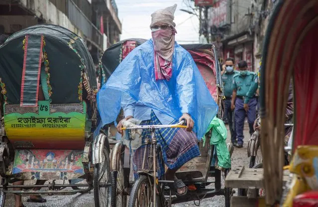 A rickshaw puller covers himself in plastic on a rainy day in Dhaka, Bangladesh, 07 September, 2021. The summer monsoon season in Bangladesh is witnessed from June through mid-October. (Photo by Monirul Alam/EPA/EFE)