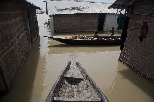 An Indian child sits in a boat as another stands near their house partially submerged in flood waters in Burgaon, 80 kilometers (50 miles) east of Gauhati, Assam state, India, Wednesday, July 5, 2017. (Photo by Anupam Nath/AP Photo)