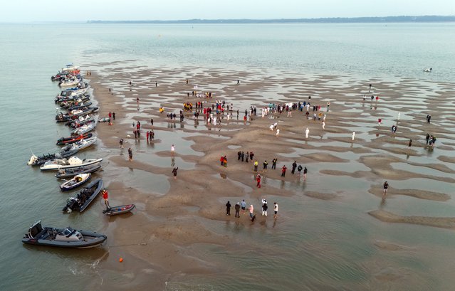 In this aerial view teams play a cricket match in the middle of the Solent on the Brambles sandbank which appears for around 30 minutes at low tide, on September 20, 2024 in Southampton, England. Members of the Island Sailing Club from the Isle of Wight and the Royal Southern Yacht Club meet for a cricket match played on the Brambles Sandbar in the middle of the Solent annually. The Sandbar emerges from the sea for about half an hour each year when the tide is at its lowest. The matches began in the 1950s and the winner is decided before the game is played. (Photo by Carl Court/Getty Images)