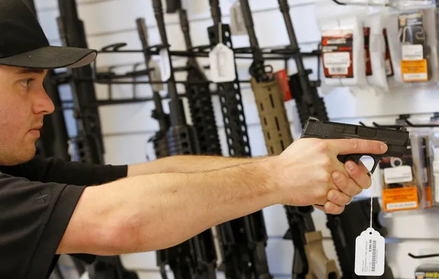 Salesman Ryan Martinez dry fires a handgun at the “Ready Gunner” gun store in Provo, Utah, U.S., June 21, 2016. (Photo by George Frey/Reuters)