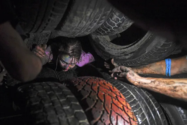 A participant crawls through tyres at the Race of Heroes night-time obstacle-course event in Novosibirsk, Russia on July 16, 2017. (Photo by Kirill Kukhmar/TASS)