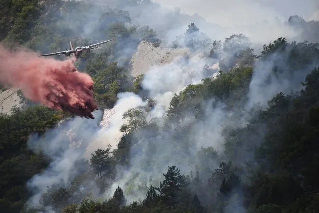 A plane drops flame retardant to put out a fire in Rigaud, north of Nice, southeastern France, on August 3, 2017. France has been battling for several weeks huge fires near beaches popular with tourists on the Cote d'Azur, forcing the evacuation of people. (Photo by Yann Coatsaliou/AFP Photo)