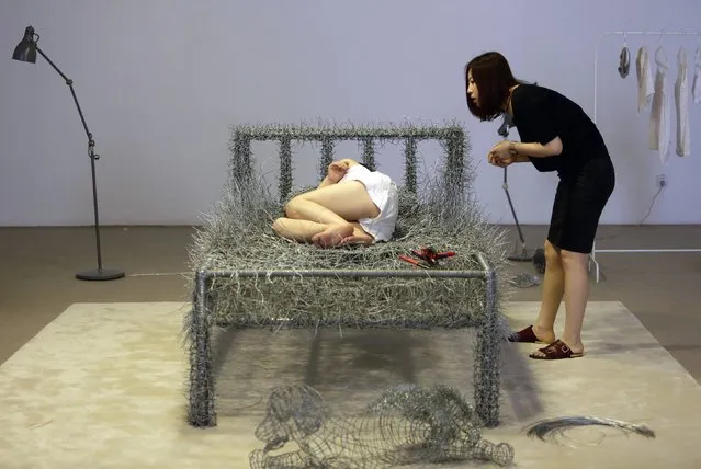 Chinese artist Zhou Jie takes a nap on an unfinished iron wire bed, one of her sculpture works, after lunch as a friend of hers looks on at Beijing Now Art Gallery, in Beijing August 11, 2014. (Photo by Jason Lee/Reuters)
