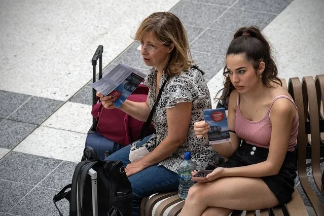 Women fan themselves with tourist brochures as they wait in Liverpool Street train station on July 18, 2022 in London, England. Temperatures were expected to hit 40C in parts of the UK this week, prompting the Met Office to issue its first red extreme heat warning in England, from London and the south-east up to York and Manchester. (Photo by Carl Court/Getty Images)