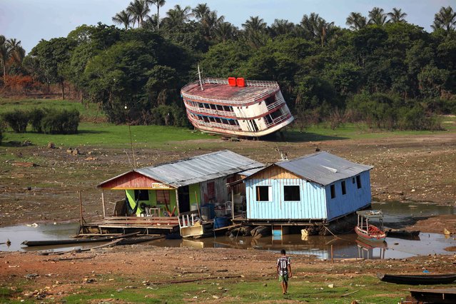Houseboats and a stranded boat are seen on the Rio Negro, in the Cacau Pirera District, in Iranduba, Amazonas, Brazil, on September 25, 2023. The Government of Amazonas declared a State of Environmental Emergency on September 12 due to the high number of fires and a strong drought in the rivers, affecting navigation and food distribution to the interior of the state. (Photo by Michael Dantas/AFP Photo)