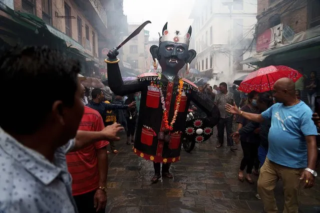 A man walks carrying an effigy of demon Ghantakarna before burning the same to represent demolition of evil during the Ghantakarna festival in Bhaktapur, Nepal, Tuesday, July 26, 2022. The festival is believed to ward off evil spirits, and bring peace and prosperity. (Photo by Niranjan Shrestha/AP Photo)