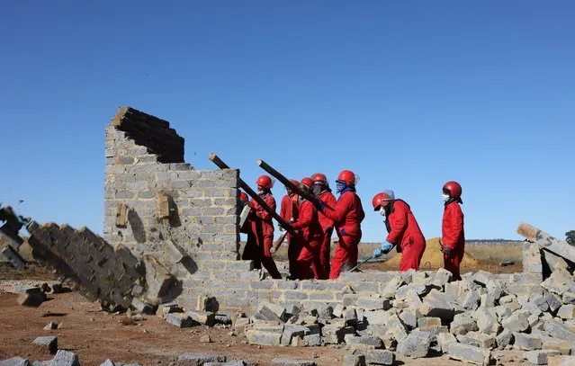 Members of the Red Ants, a South African private security company specialising in clearing “illegal invaders” from properties, demolish an illegally built structure, amid the spread of the coronavirus disease (COVID-19), in Lawley township, south of Johannesburg, South Africa April 16, 2020. (Photo by Siphiwe Sibeko/Reuters)