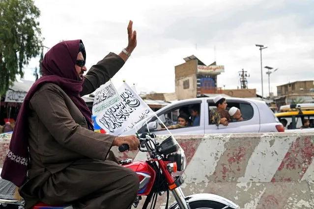 A Taliban fighter rides a motorcycle while taking part in a parade during the celebrations to mark the first anniversary of the withdrawal of US-led troops from Afghanistan, in Kandahar on August 31, 2022. The Taliban declared on August 31 a national holiday and lit up the capital with coloured lights to celebrate the first anniversary of the withdrawal of US-led troops from Afghanistan after a brutal 20-year war. (Photo by Javed Tanveer/AFP Photo)