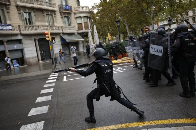 Spanish riot police shoots rubber bullet straight to people trying to reach a voting site at a school assigned to be a polling station by the Catalan government in Barcelona, Spain, Sunday, October 1, 2017. Spanish riot police have forcefully removed a few hundred would-be voters from several polling stations in Barcelona. (Photo by Emilio Morenatti/AP Photo)