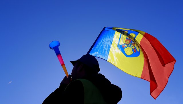 A trade unionist member belonging to Railway union federation blows a plastic trumpet while waving the national flag during a protest held in front of the government headquarters in Bucharest, Romania, 16 November 2023. Hundreds of members of the Railway Union, the Foresters' Union, the Laid-off Military Union and Local Police Union, from all over the country, gathered in Romania's capital to protest against the new Public Pension System Law. Most of these unionists have their speciffic activities in heavy or dangerous working conditions, fact that is no longer recognized or compensated by the new pension law system. (Photo by Robert Ghement/EPA/EFE)
