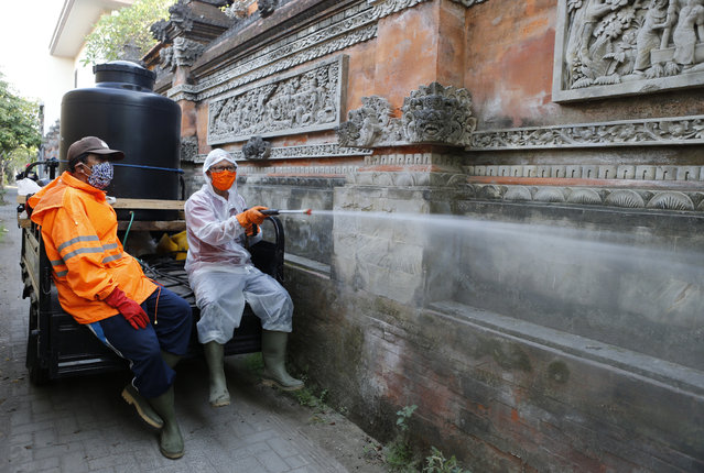 Municipality workers spray disinfectant to help reduce the spread of the coronavirus along a detailed wall in a local neighborhood in Bali, Indonesia, Tuesday, May 5, 2020. (Photo by Firdia Lisnawati/AP Photo)