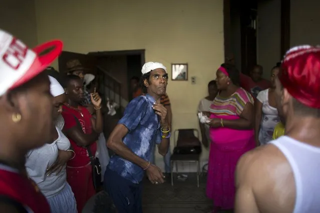 Santeria practitioner Humberto Cuevas (C) undergoes a brief fit of spirit-induced convulsions during a ceremony to attract spirits of dead ancestors to ask for guidance in downtown Havana, August 18, 2015. (Photo by Alexandre Meneghini/Reuters)
