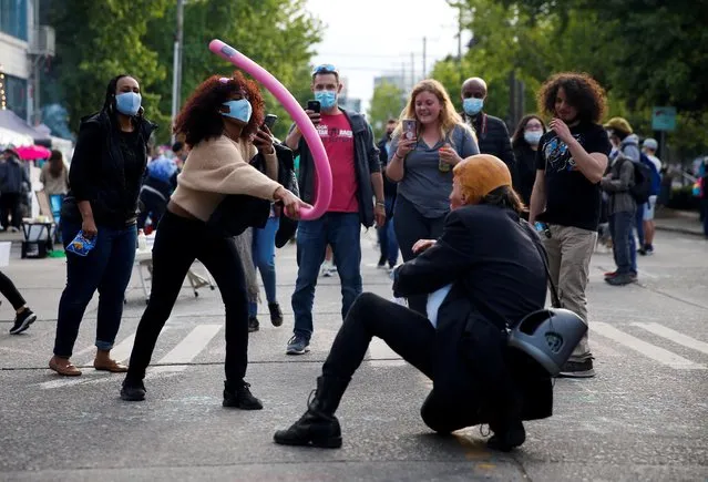 A woman hits a person wearing a mask of U.S. President Donald Trump with a pool noodle at the CHAZ/CHOP zone near the Seattle Police Department's East Precinct during continued protests against racial inequality and the police in the aftermath of the death in Minneapolis police custody of George Floyd, in Seattle, Washington, U.S. June 14, 2020. (Photo by Lindsey Wasson/Reuters)