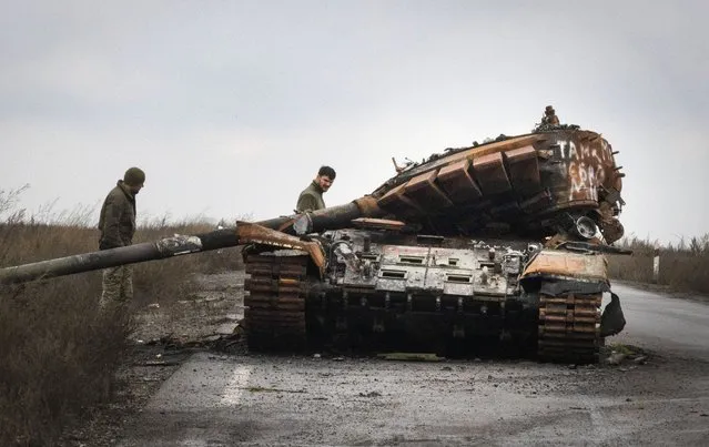 Ukrainian soldiers inspect a damaged Russian tank on a road near the recently retaken village of Kamianka, Kharkiv region, Ukraine, Sunday, October 30, 2022. (Photo by Efrem Lukatsky/AP Photo)
