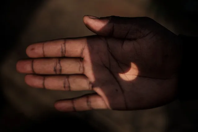 The partial solar eclipse is projected on a Kenyan man's hand through binoculars in Nairobi, Kenya on June 21, 2020. (Photo by Yasuyoshi Chiba/AFP Photo)