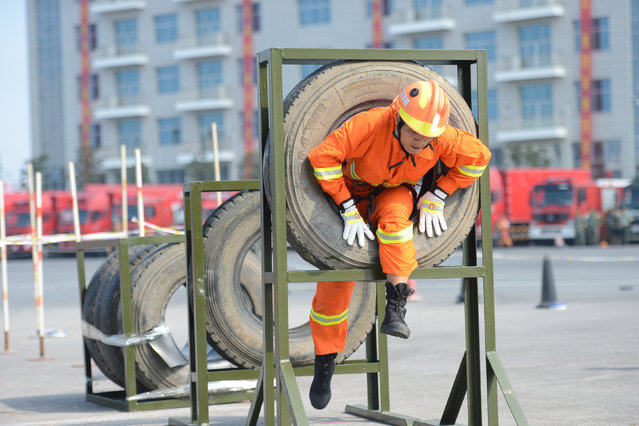 A fire fighter climbs out from a tire during an exercise in Weifang, Shandong, China, August 16, 2016. (Photo by Reuters/Stringer)