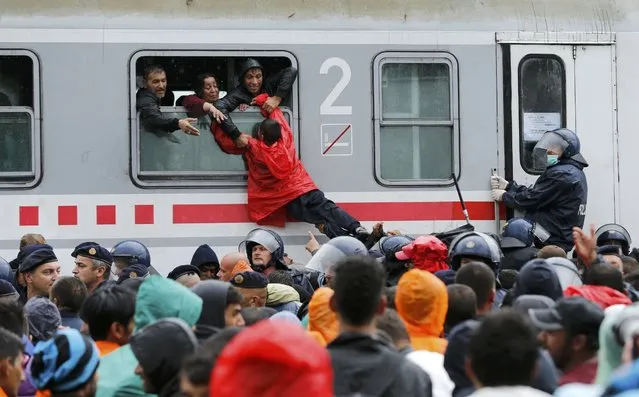 Migrants pull a boy through a train window at the station in Tovarnik, Croatia, September 20, 2015. (Photo by Antonio Bronic/Reuters)