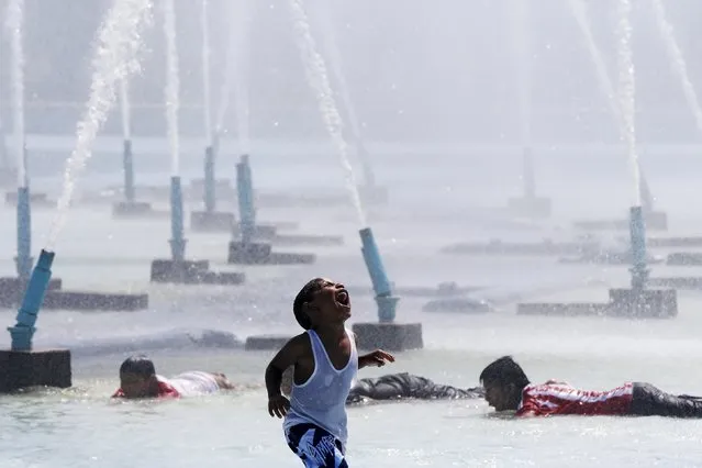 A child smiles while cooling off in the water at the Unisphere at Flushing MeadowsÐCorona Park in the Queens borough of New York August 18, 2015. (Photo by Shannon Stapleton/Reuters)