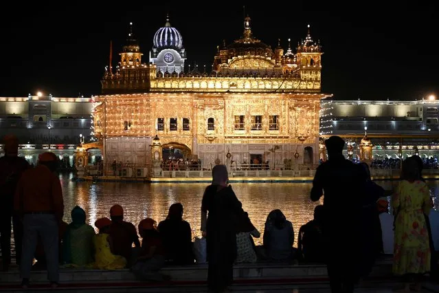 Devotees visit the illuminated Golden Temple on the eve of the birth anniversary of Guru Nanak Dev, the founder of Sikhism, in Amritsar on November 7, 2022. (Photo by Narinder Nanu/AFP Photo)