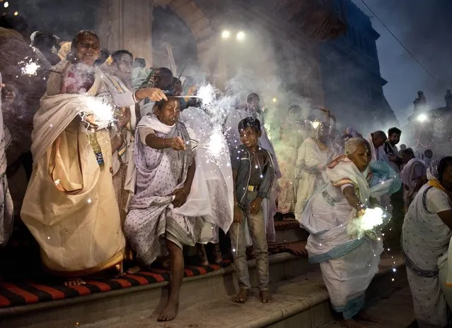 Indian widows wave sparklers as they participate in a celebration for the Hindu festival Diwali on the banks of the Yamuna river in the northern city of Vrindavan on October 21, 2014. The women, who chanted as they walked through the streets of Vrindavan to mark the Hindu festival of Diwali, are widows who have left or been abandoned by their families. (Photo by Roberto Schmidt/AFP Photo)